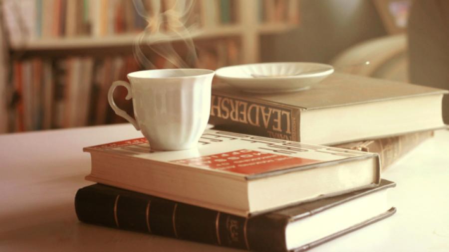 Foto af dampende kaffekop oven på en stak bøger
