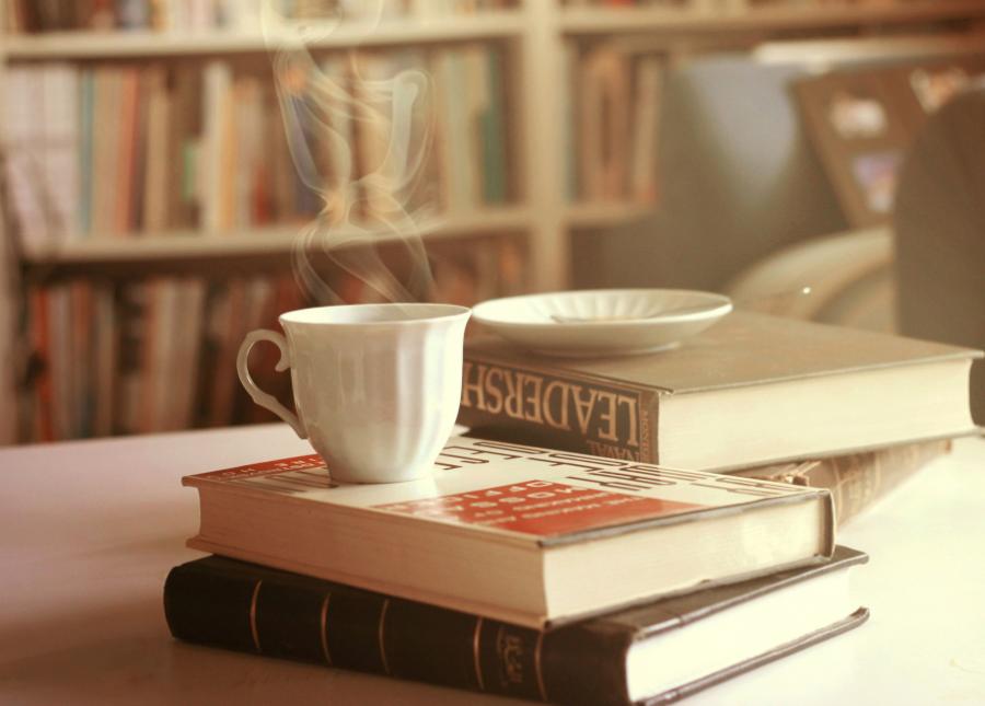 Foto af dampende kaffekop oven på en stak bøger